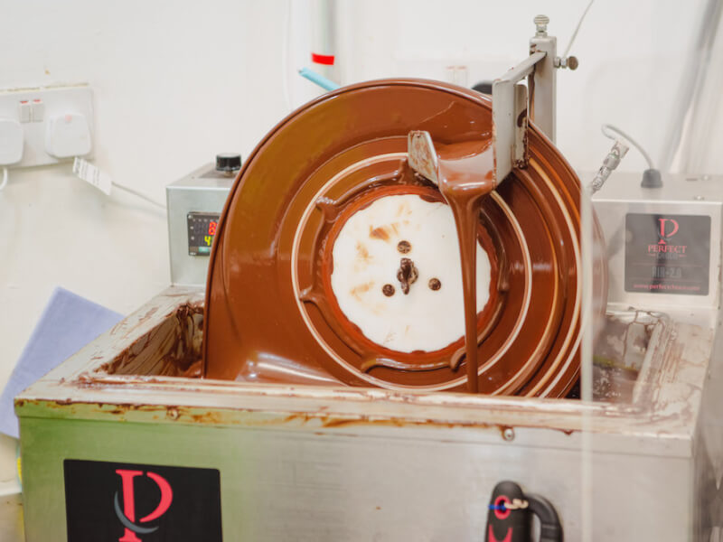 A big chocolate making wheel turns full of milk chocolate at a chocolate class